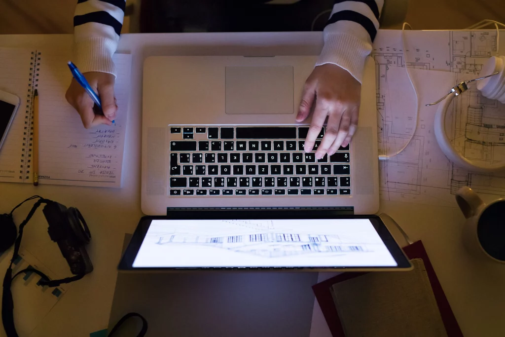 Unrecognizable woman sitting at desk working on laptop.