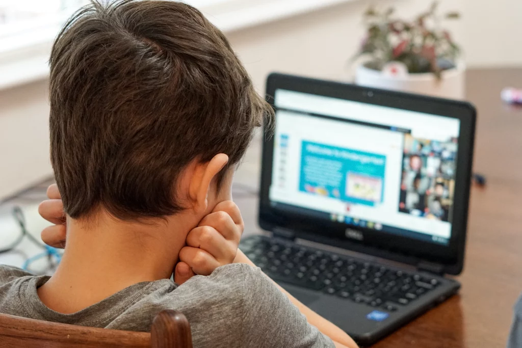 child doing virtual back-to-school on laptop on kitchen table