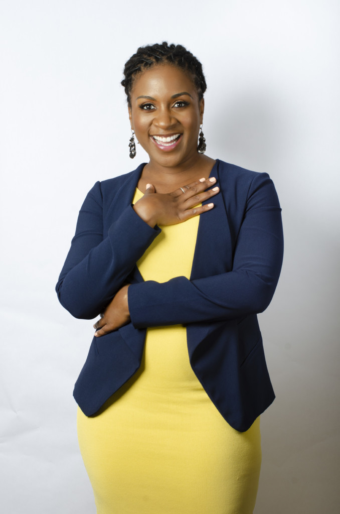 Jennifer Tardy posing in yellow drress with hand on chest