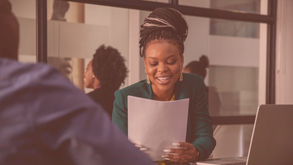 woman in green blazer holding paper asking interview questions